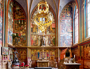 Grand church interior with vibrant frescoes and golden chandelie