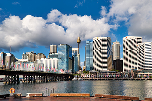 Sydney Harbour skyline with bridge and buildings under clouds.