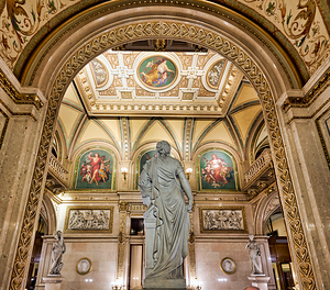 Ornate hall with classical statue and elaborate ceiling art.