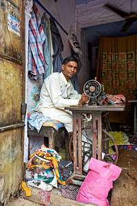 Man sewing clothes in Bundi Rajasthan during the day by Marco Brivio
