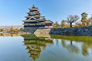 Matsumoto Castle reflects in the water on a clear day in Japan