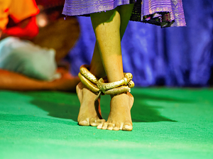 Bare feet with golden anklets on green surface.