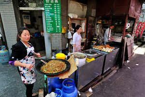 Vendors prepare noodles and fried items in Shanghai street marke