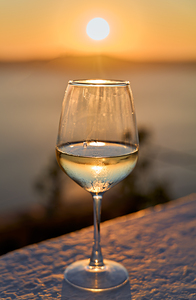 Wine glass reflecting golden sunset over water.