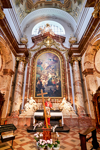 Baroque church interior altar painting and saint statue.