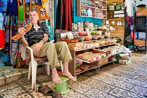 Old city shop in Jerusalem with man sitting and enjoying a snack
