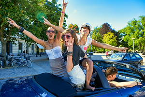 Young women enjoy a fun time on a car in Stockholm by Marco Brivio