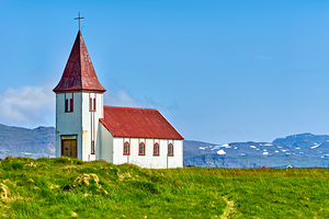 Church in Hellnar Iceland stands against blue sky and mountains