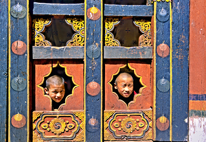 Young monks peeking from decorative colorful windows.