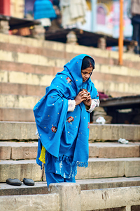 Woman praying by the Ganges in Varanasi during morning hours
