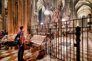 Man observes prayer candles in a grand cathedral.