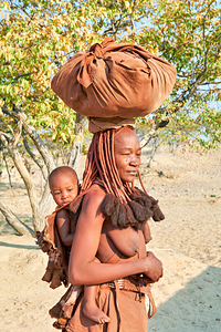 Himba woman carries baby in Kunene region of Namibia