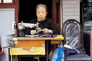 Elderly woman sews at machine in Shanghai China by Marco Brivio