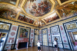 Two people explore the decorated room at the Palace of Versaille