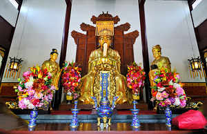 Golden deity statues in Shanghai temple with floral offerings