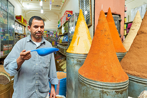 Sale of spices in Marrakesh souk with vendor showing products