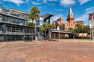 Modern building and historic tower by the water.