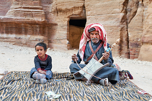 Musician performs in Petra Jordan with a child nearby
