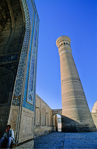 People rest near the tall minaret in Khiva Uzbekistan