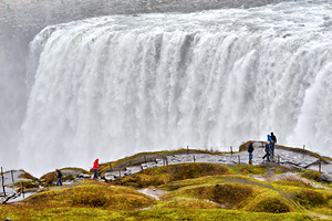 Visitors by Dettifoss waterfall in cloudy Iceland
