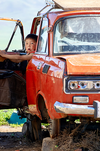 Boy sits in a wrecked car in Mongolia