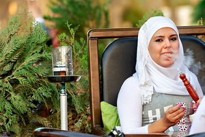 Young woman smokes hookah in outdoor cafe in Aleppo Syria