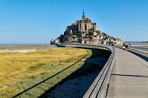 Tourists walking on bridge to Mont Saint Michel in Normandy Fran
