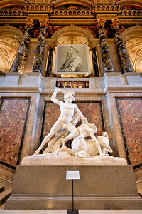 Marble sculpture of man fighting centaur in ornate museum hall.