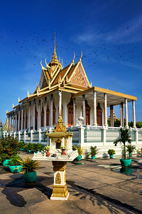 Majestic Cambodian temple under a blue sky with flying birds.