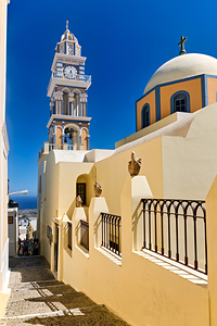 Iconic Santorini church and clock tower under blue sky. by Marco Brivio