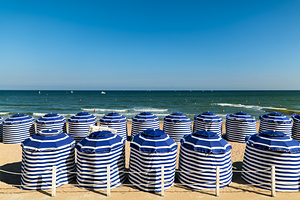 Beach scene in Cabourg Normandy with striped umbrellas on sand