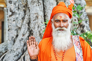 Sadhu in orange robe stands near tree in Jaipur Rajasthan