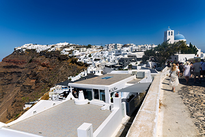 Santorini village on cliff with white buildings and blue domed c