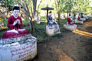 Sacred Buddha statues in Myanmar among trees and sunlight