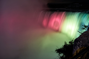 Niagara Falls illuminated at night with colorful lights.