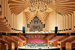 Orchestra rehearses in a modern concert hall with wooden interio