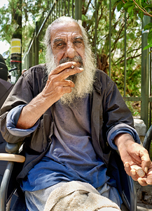 Man sitting outdoors while smoking a cigarette in the city