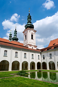 Historic monastery courtyard with pond and prominent towers unde
