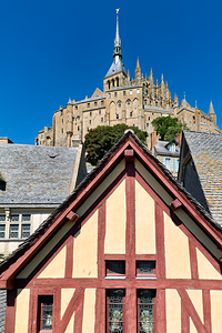 Mont Saint Michel rises above houses in Normandy France on a sun