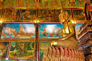 Golden Buddha statue and intricate murals in a temple.