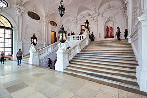 Visitors exploring a grand ornate staircase in a historic palac