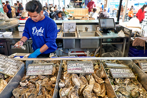 Oyster vendor prepares fresh oysters for customers at market.