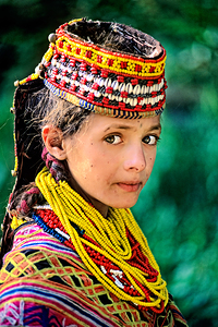 Kalash woman in traditional attire stands outdoors in Pakistan