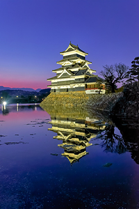 Matsumoto Castle at sunset with reflection in water in Japan