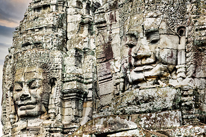Serene stone faces adorn ancient Cambodian temple.