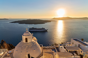 Golden sunset over Santorini caldera with cruise ship and church