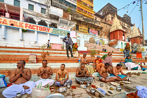 Barechested men offer prayers by the Ganges River in Varanasi