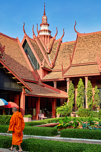 Monk walks through traditional Cambodian temple garden.