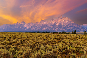 Hikers explore view of Grand Teton mountains at sunset