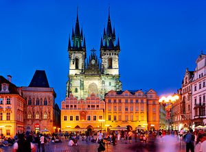 Pragues Old Town Square at night illuminated church and crowd.